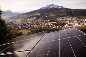 Toit avec modules solaires installés devant un panorama montagneux. 