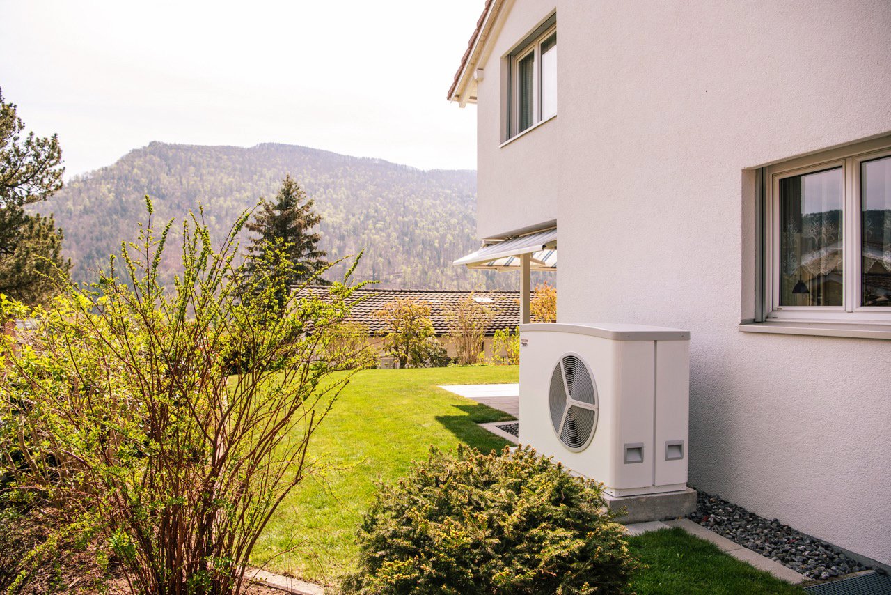 Vista sul lato di una casa unifamiliare dotata di una pompa di calore. 